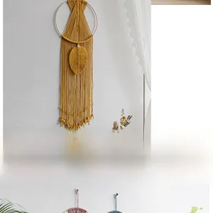Detail of handmade yellow cotton macrame wall hanging with woven leaf and tassel fringe