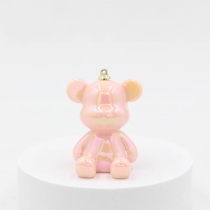 Pink pearlescent bear keychain with metallic finish and gold ring on display stand