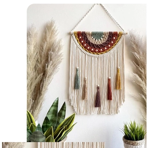 Detail of bohemian woven wall decor with rainbow patterns, earthy fringes and wooden beads