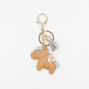 Porte-clés cheval en cuir marron avec breloque sac doré et gland gris sur fond blanc