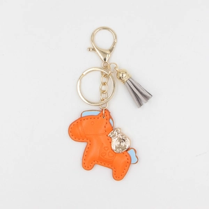 Porte-clés cheval en cuir orange avec breloque sac d'argent doré et pompon gris clair