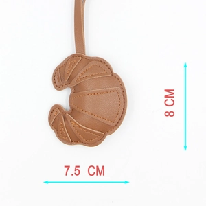 Detail view of croissant-shaped PU leather keychain with stitching and 8cm x 7.5cm dimensions