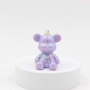 Purple laser resin bear keychain with shiny iridescent finish on a white round display