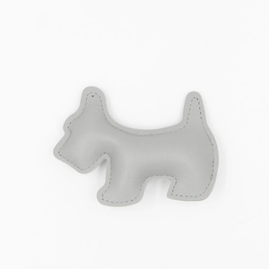 Close-up of grey litchi grain leather puppy bag charm with refined stitching details
