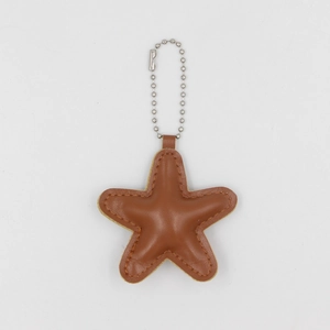 Detail view of a star-shaped tan faux leather keychain with silver bead chain and stitching