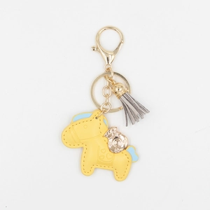 Détail d'un porte-clés cheval en cuir jaune avec métal doré et pompon gris élégant