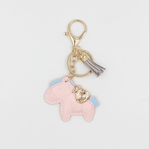Détail d'un porte-clés cheval en cuir rose clair avec crinière bleue et breloque dorée