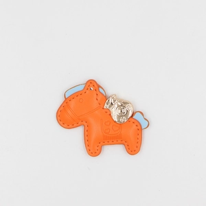 Orange leather horse bag charm with blue details and gold-tone lucky bag pendant accessory