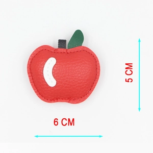 Détail d'un porte-clés pomme 3D en cuir rouge montrant la texture grainée et la taille 6x5cm