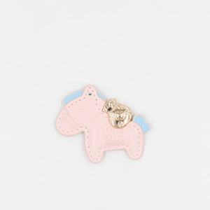 Close-up of pink faux leather horse keychain with handmade stitching and gold lucky bag charm