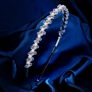 Detail eines silbernen Haarreifs mit Kristallperlen und Perlen auf blauem Satin