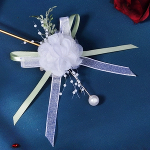 Detail of white tulle boutonniere with satin ribbons and elegant pearl accents