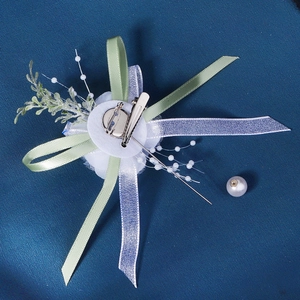 White chiffon flower boutonniere with green ribbons and pearls for wedding events