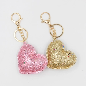 Vue macro de porte-clés cœur à paillettes roses et dorées avec fermoirs mousquetons en métal doré