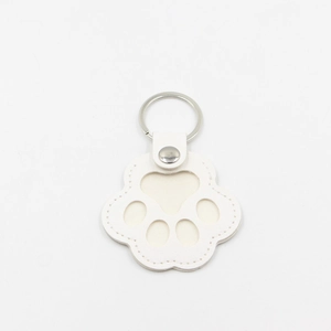 Close-up of white leather cat paw keychain with silver metal ring and fine stitching
