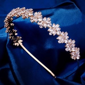Détail macro du serre-tête doré avec fleurs en cristal sur fond de soie bleue