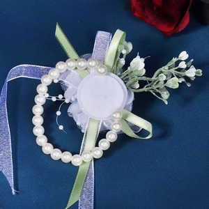 Detail of white tulle flower wrist corsage with pearls and greenery for bridesmaids