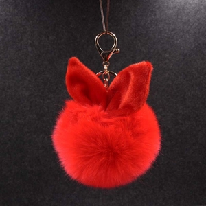 Détail d'un porte-clés pompon rouge aux oreilles de lapin avec fermoir doré brillant
