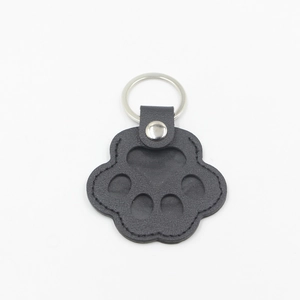Close-up of black leather cat paw keychain with silver metal ring and snap button