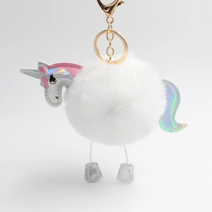 Detailed macro of white plush unicorn pompom keychain with holographic wings and gold clasp