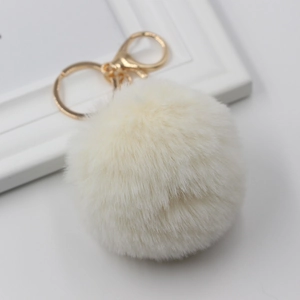 Close-up of fluffy white faux fur pompom keychain with elegant golden metal lobster clasp