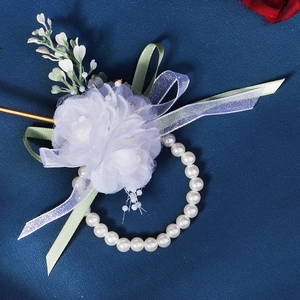 Macro detail of white silk flower wrist corsage with faux pearls and ribbon