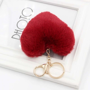 Close-up of soft red heart plush keychain with golden metal clasp on white frame