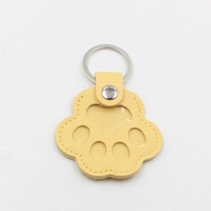 Detail of yellow cat paw leather keychain with transparent window and silver ring