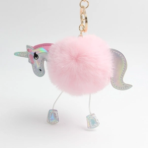 Detail of pink fluffy unicorn pompom keychain with holographic leather and gold hardware