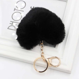 Close-up of black heart-shaped faux fur keychain with golden clasp on white background