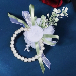 Detail of white chiffon flower wrist corsage with pearls and blue satin ribbons