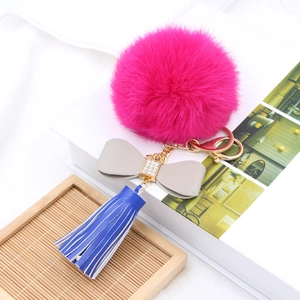 Detail of plush pompom keychain with rhinestone bow, leather tassel and golden hardware