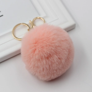 Detail view of a soft pink faux rabbit fur pom pom keychain with golden metal clasp