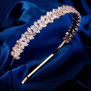 Détail d'un serre-tête doré avec zircons marquise sur un tissu en soie bleu foncé