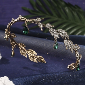 Detailed macro view of vintage gold leaf crown with sparkling green water-drop pendants