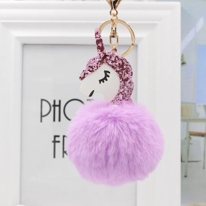 Einhorn Plüsch Schlüsselanhänger mit pinkem Glitzerhorn und lila Bommel vor Bilderrahmen
