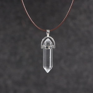 Macro view of hexagonal clear crystal pendant with silver setting and brown wax cord