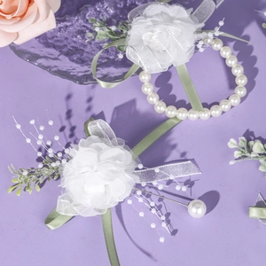 Detail of white tulle wedding corsage and wristlet set with pearls and greenery