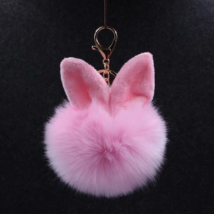 Gros plan du porte-clés pompon rose duveteux avec oreilles de lapin et fermoir doré