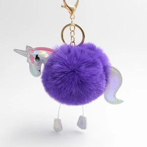 Detailed close-up of purple unicorn pompom keychain with golden metal clasp and holographic parts