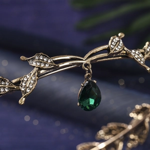 Detail of vintage bronze branch tiara with shimmering crystals and green teardrop gem