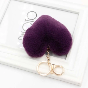 Detailed close-up of a soft purple heart-shaped faux fur pom pom with gold metal hardware