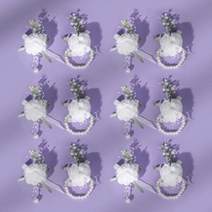 Detail of white tulle wedding corsage and wristlet with pearls and green leaves