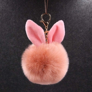 Détail d'un porte-clés pompon oreille de lapin rose pêche avec fermoir mousqueton doré