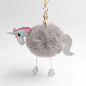 Detail of unicorn plush keychain featuring grey faux fur ball and iridescent silver accents