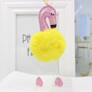 Close-up of pink flamingo plush keychain with yellow pompom and gold metal buckle