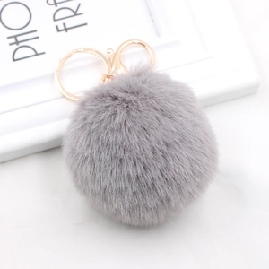 Detailed close-up of fluffy gray faux rabbit fur pompom with golden metal clasp