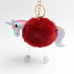 Detail of red pompom unicorn keychain with holographic silver leather and golden hardware
