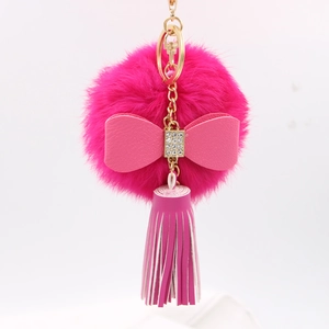 Close-up of rose pink plush pompom keychain with rhinestone bow and long fringe tassel