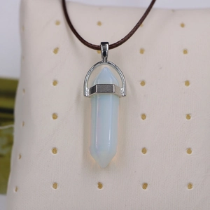 Macro view of a hexagonal opal crystal pendant with a silver clasp on a brown cord